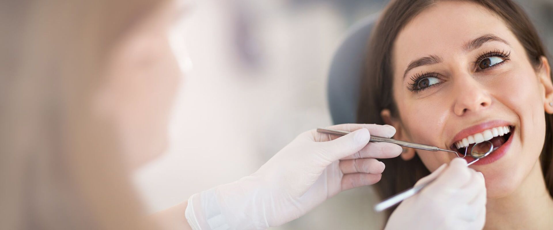 Zahnärztliche Untersuchung bei einer lächelnden Patientin im Behandlungsstuhl